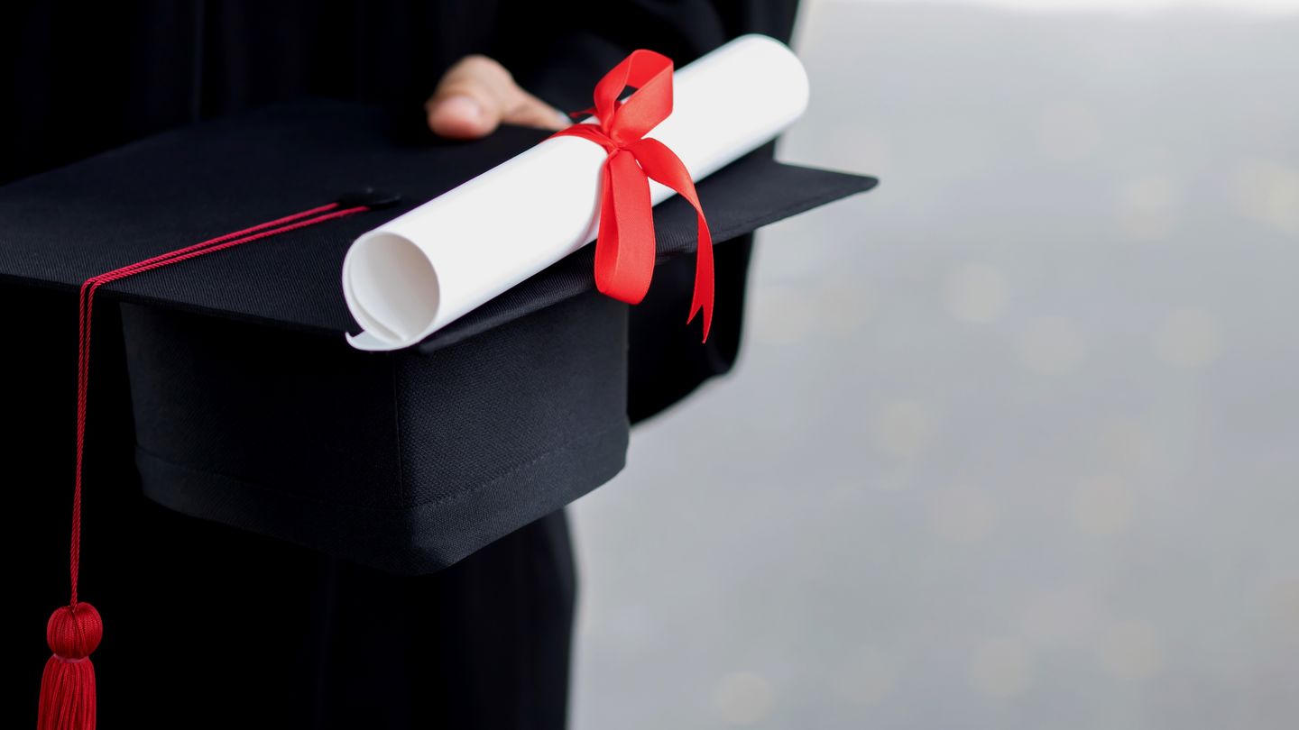 Degree: Graduate holds her Master's hat and Master's certificate in her hand. Photo: © Rattankun Thongbun/Getty Images/iStockphoto