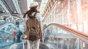 [Translate to English:] Eine Studierende mit Rucksack und Koffer am Flughafen. Foto: Getty Images