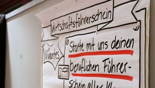 Handgeschriebene Tafel mit der Überschrift 'Wirtschaftsführerschein' und dem Text 'Starte mit uns deinen beruflichen Führerschein aller Klassen' unterstrichen mit rotem Marker.