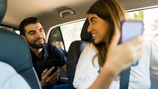 Eine Frau und ein Mann im Auto mit einem Handy in der Hand