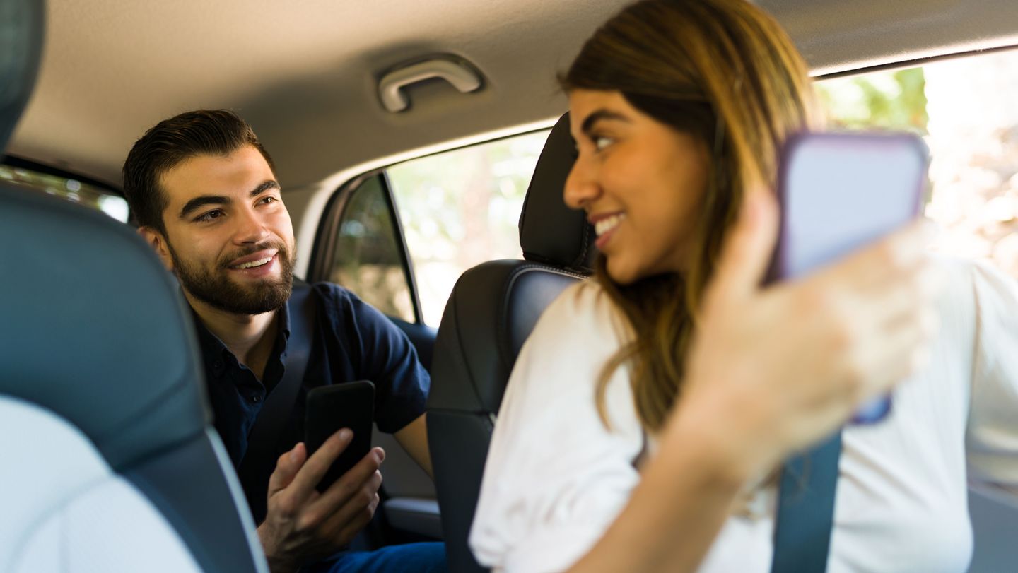 Eine Frau und ein Mann im Auto mit einem Handy in der Hand