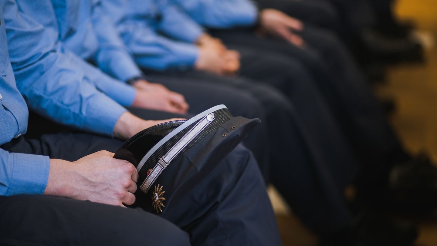 Polizeibeamte in Uniform sitzen in einer Reihe, mit ihrer Dienstmütze im Schoß. Foto: Oana Popa-Costea