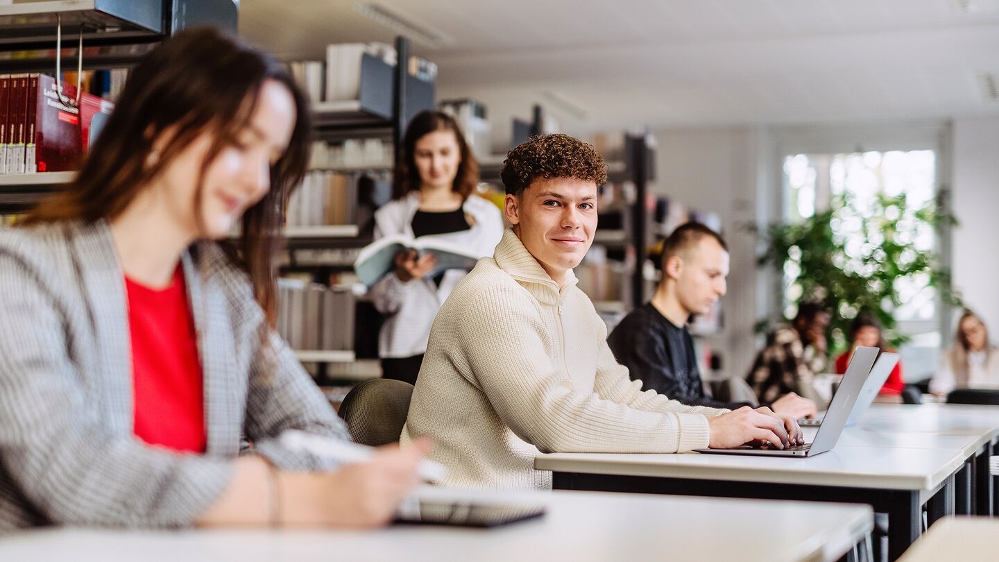 Dual studieren an der HWR Berlin: Vier Studierende arbeiten in der Bibliothek am Laptop. Foto: Lukas Schramm