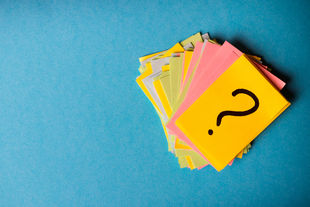 A stack of different coloured Post-it notes in a pile. The top Post-it has a black question mark on it. Photo: © Mykola Sosiukin/Getty Images/iStockphoto