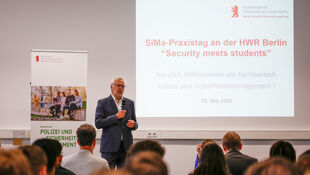 Vortragender steht vor Leinwand mit Präsentation zum Thema "SiMa-Praxistag an der HWR Berlin Security meets students" vor Publikum in einem Seminarraum.