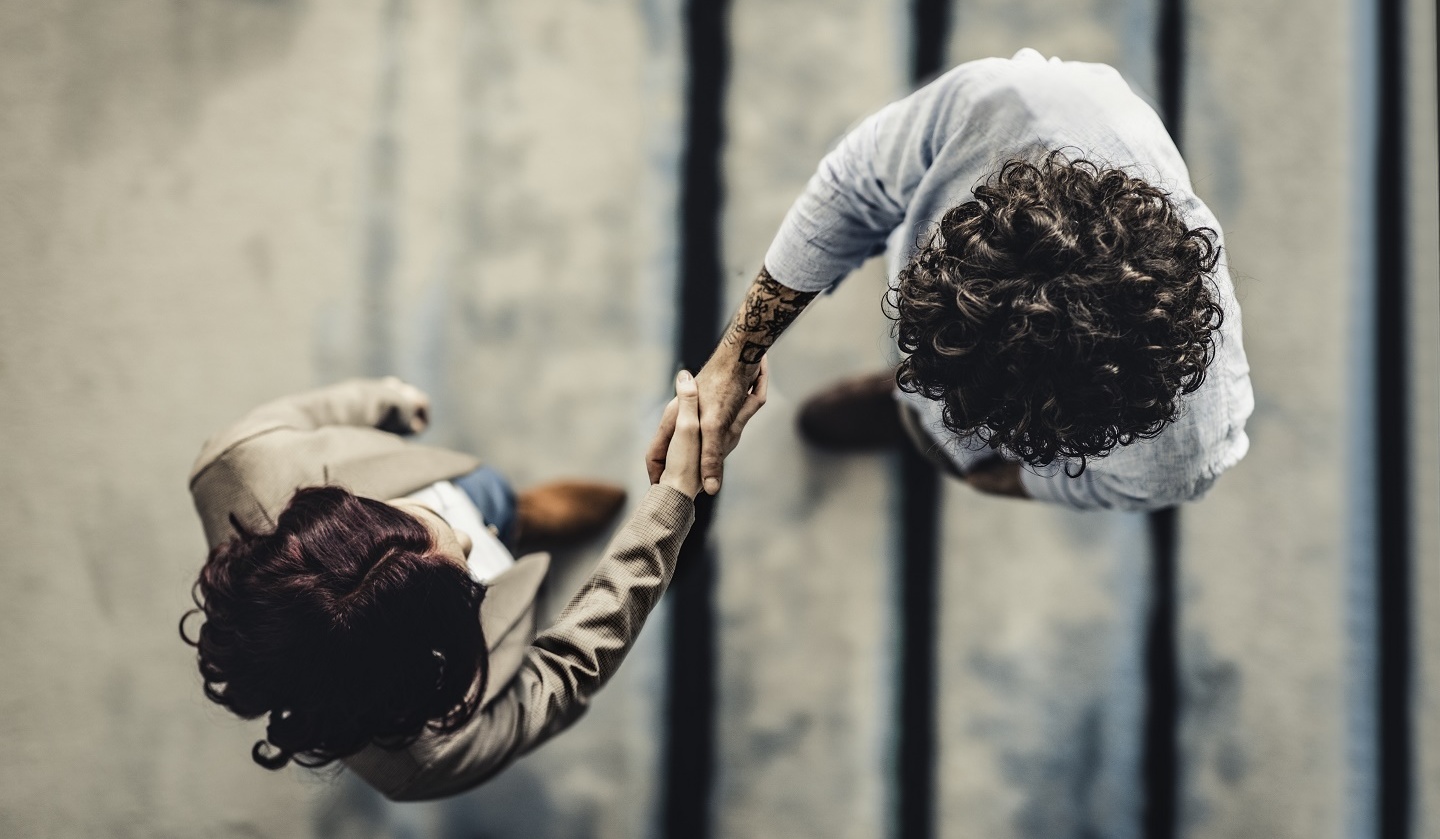 Kameraperspektive von oben: Ein Mann und eine  Frau schütteln sich die Hand. Foto: © nimis69/E+/Getty Images