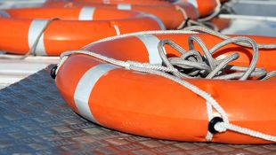 Two orange lifesaving rings are placed on the edge of a swimming pool. Photo: © Pobytov/E+/Getty Images