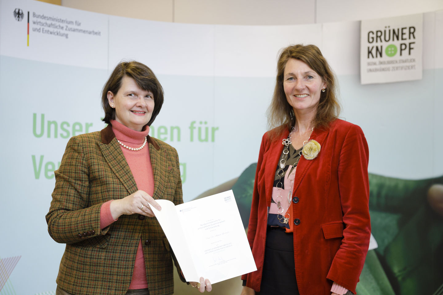 Dr. Maria Flachsbarth vom Bundesentwicklungsministerium überreicht Prof. Dr. Stefanie Lorenzen von der HWR Berlin (rechts im Bild) die Ernennungsurkunde als Mitglied des Expert/innenbeirats des Textilsiegels „Grüner Knopf“.