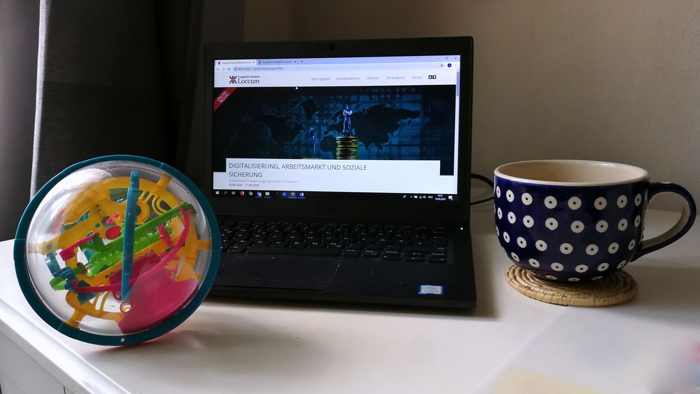 Laptop, rechts daneben eine Kaffetasse, links daneben ein buntes Logikspiel.