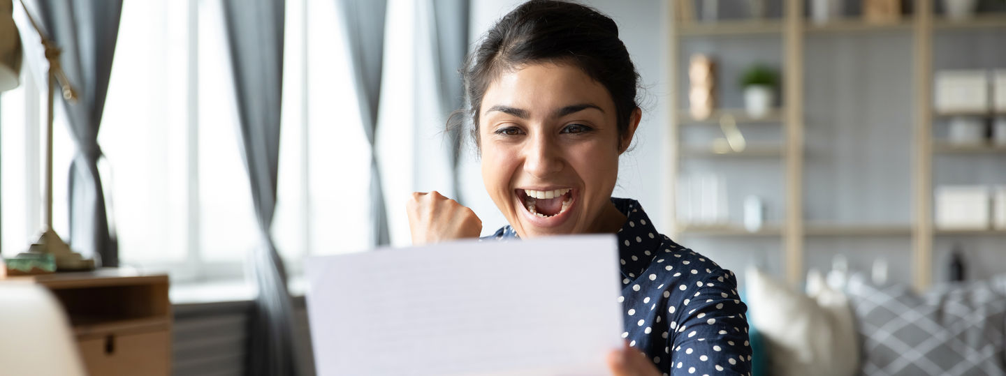 Stipendien und Auszeichnungen an der HWR Berlin: Studierende im blau-weißen Oberteil freut sich über einen Zusage-Brief, den sie in der Hand hält. Foto: © fizkes/Getty Images/iStockphoto