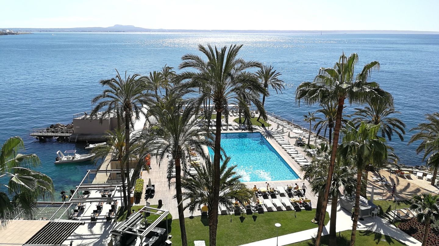 Blick vom Balkon auf eine große Ferienanlage mit Pool und umringt vom Meer.