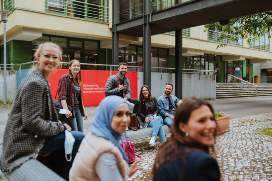 Summer semester 2022: Students of the HWR Berlin sit in the courtyard in front of the entrance to the university at the Lichtenberg campus. Photo: Oana Popa-Costea