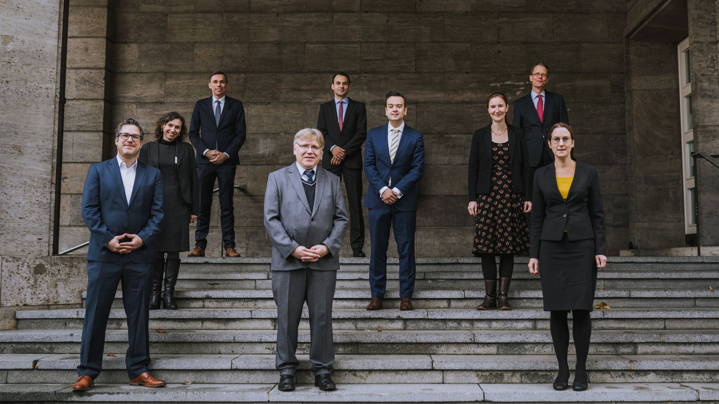 Personen stehen mit Abstand zueinander auf einer Treppe.