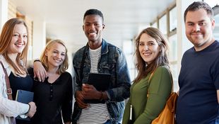 Bachelor-Bewerbung an der HWR Berlin: Drei weibliche und zwei männliche Studierende lächeln in die Kamera. Foto: © LumiNola/E+/Getty Images