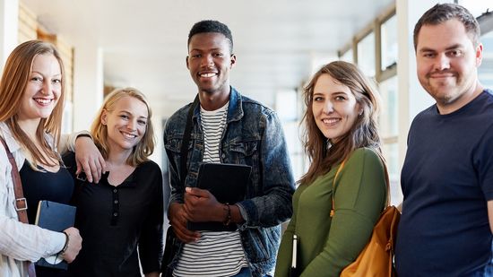 Bachelor-Bewerbung an der HWR Berlin: Drei weibliche und zwei männliche Studierende lächeln in die Kamera. Foto: © LumiNola/E+/Getty Images