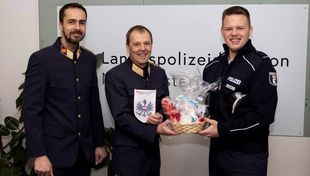 Drei Männer in Polzeiuniform mit einem Präsentkorb