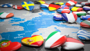 Karte von Europa mit Herzmagneten in den Flaggenfarben verschiedener Länder wie Schweden, Dänemark, Frankreich, Spanien, Italien und Griechenland