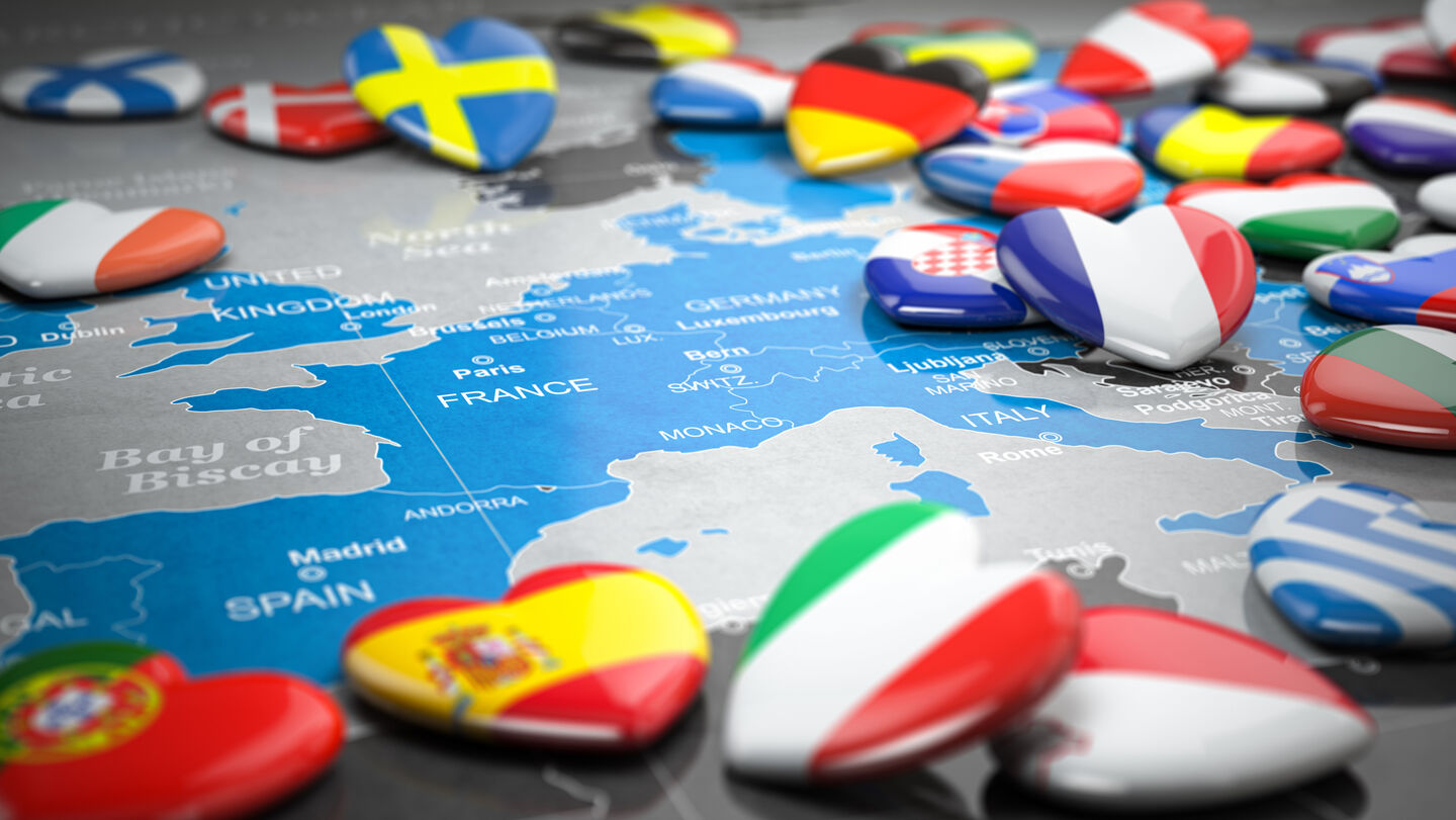 Karte von Europa mit Herzmagneten in den Flaggenfarben verschiedener Länder wie Schweden, Dänemark, Frankreich, Spanien, Italien und Griechenland