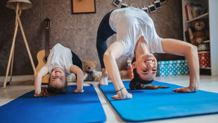 Mutter und Tochter machen Yoga im Wohnzimmer. Foto: Getty Images