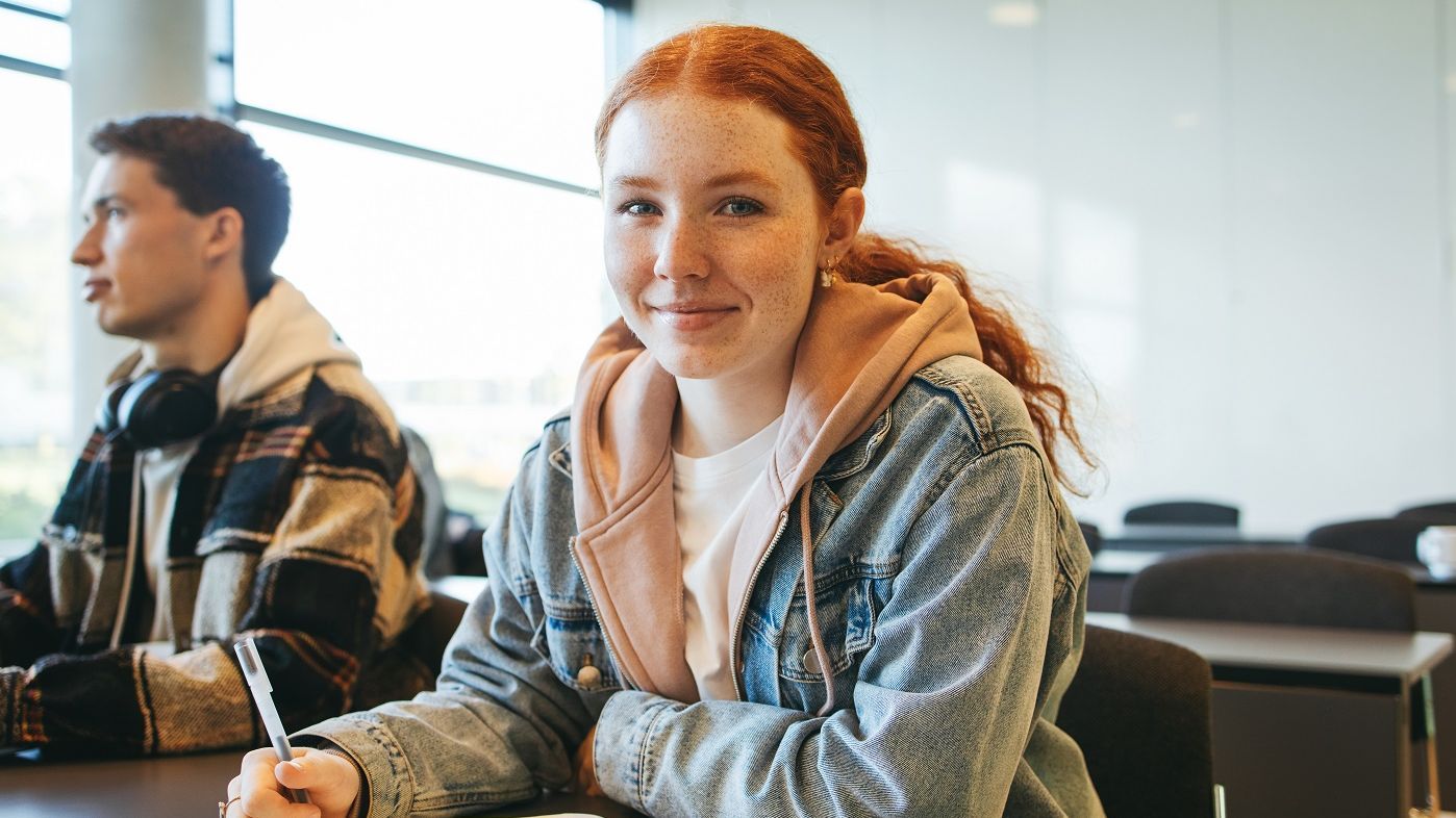 Schülerin sitzt in einem Klassenraum an einem Tisch.
