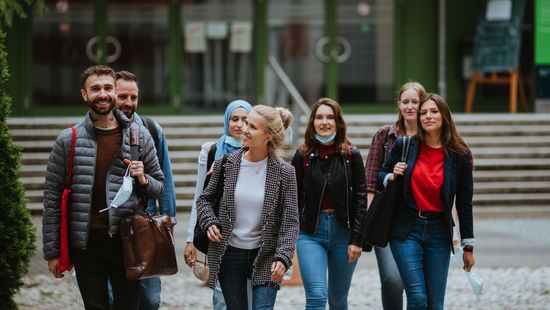 Dual studieren an der HWR Berlin: Eine Gruppe von Studierenden vor dem Eingang der Hochschule am Campus Lichtenberg. Foto: Oana Popa Costea
