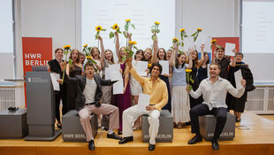 Gruppe von jungen Menschen auf einer Bühne, die Sonnenblumen und Urkunden hochhalten und jubeln