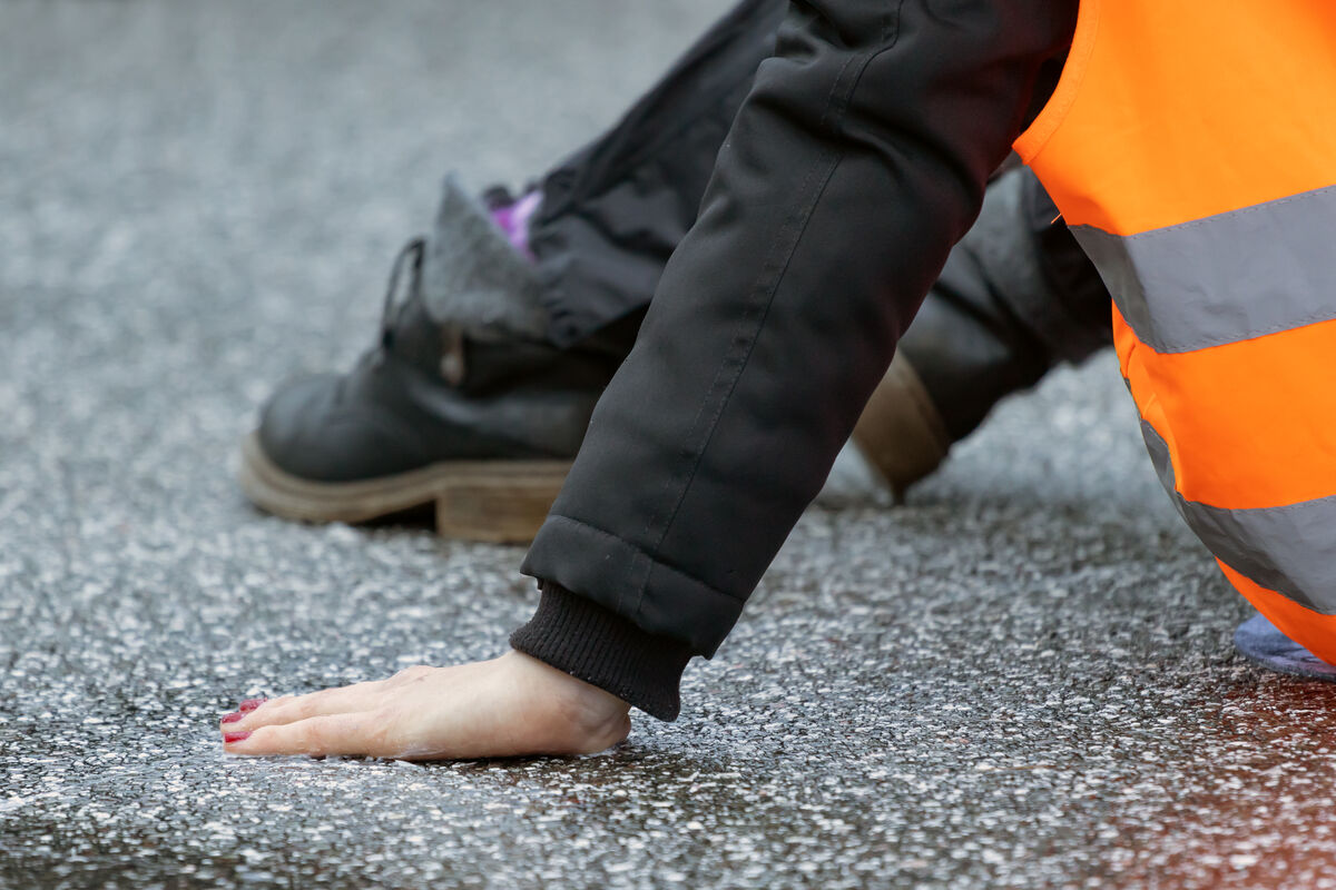 Aktivist*in der Letzten Generation klebt auf der Straße