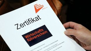 Person hat Zertifikat "Wirtschaftsführerschein" in der Hand