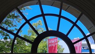 Fahne der HWR Berlin hinter einem Fenster.