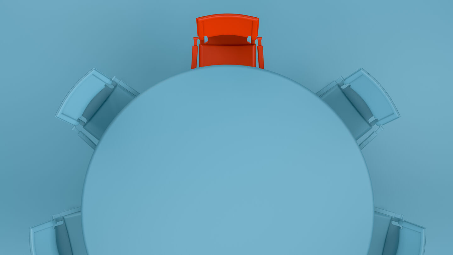Von oben: Runder Konferenztisch mit vier blauen und einem roten Stuhl