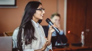 Students hold a microphone in their hands addressing the student parliament. Photo: © sanjeri/Getty Images/E+