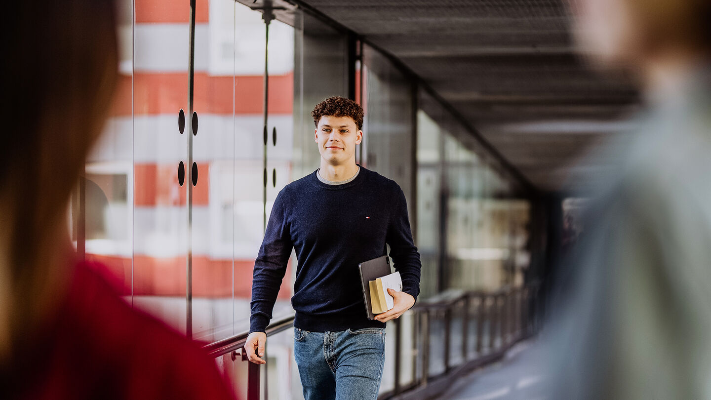 Student läuft durch einen gläsernden Gang am Campus Lichtenberg. 