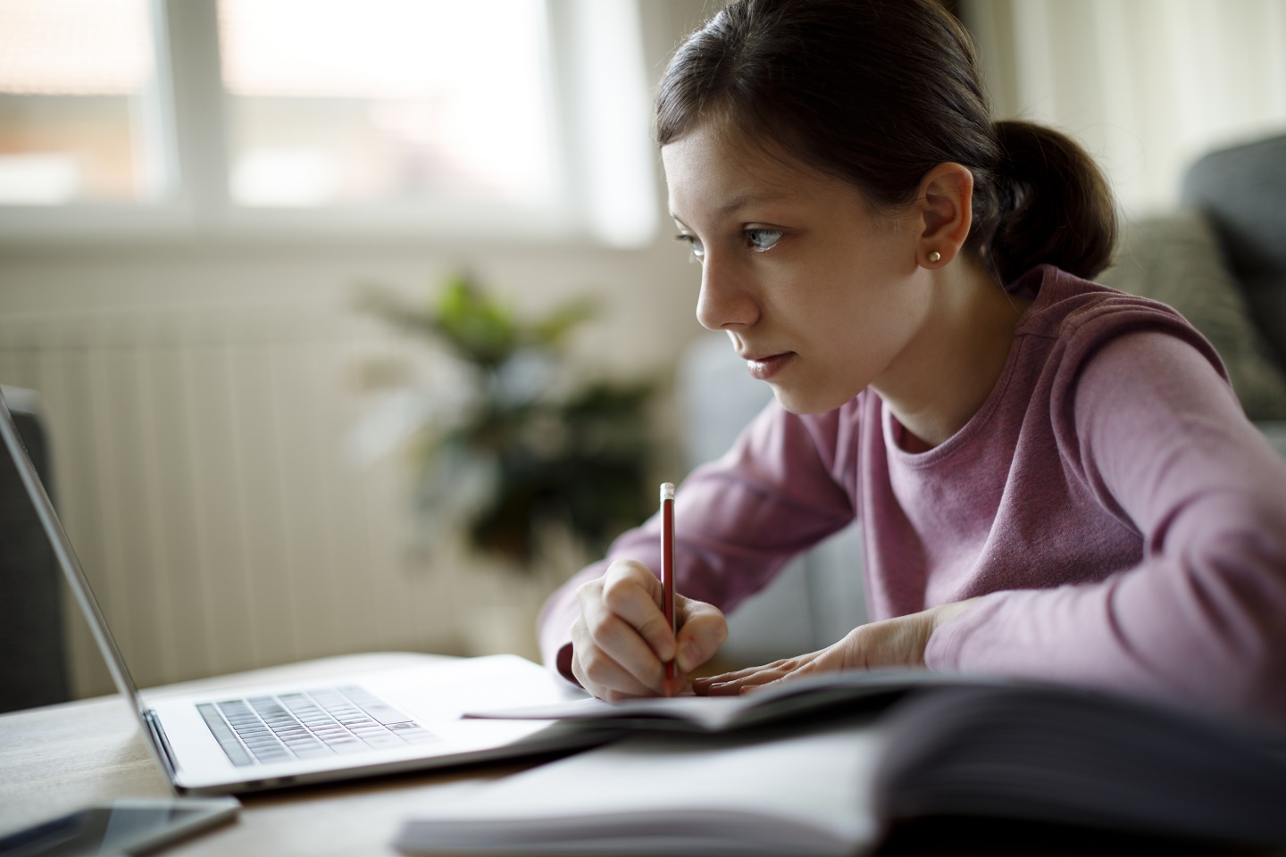 Digitaler Austausch zwischen der Coventry University und der HWR Berlin: Im November 2020 fand im Rahmen des internationalen Projekts Toolip der erste »Virtual Global Classroom« statt. Foto: © damircudic/E+/Getty Images Virtual Global Classroom: Studierende arbeitet zu Hause am Laptop und macht sich Notizen. Foto: © damircudic/E+/Getty Images